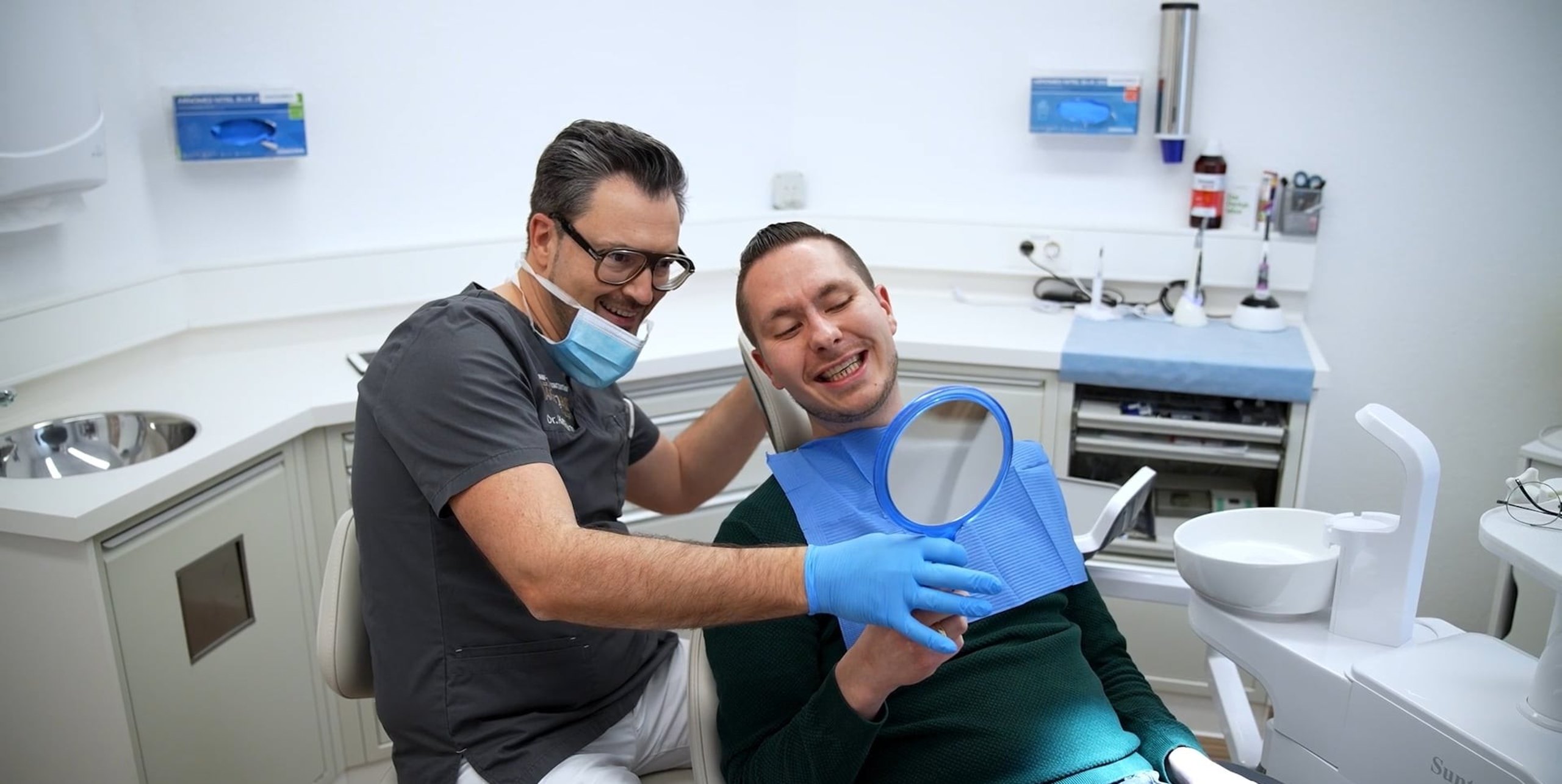 Patient lächelt überglücklich mit neuen festen Zähnen